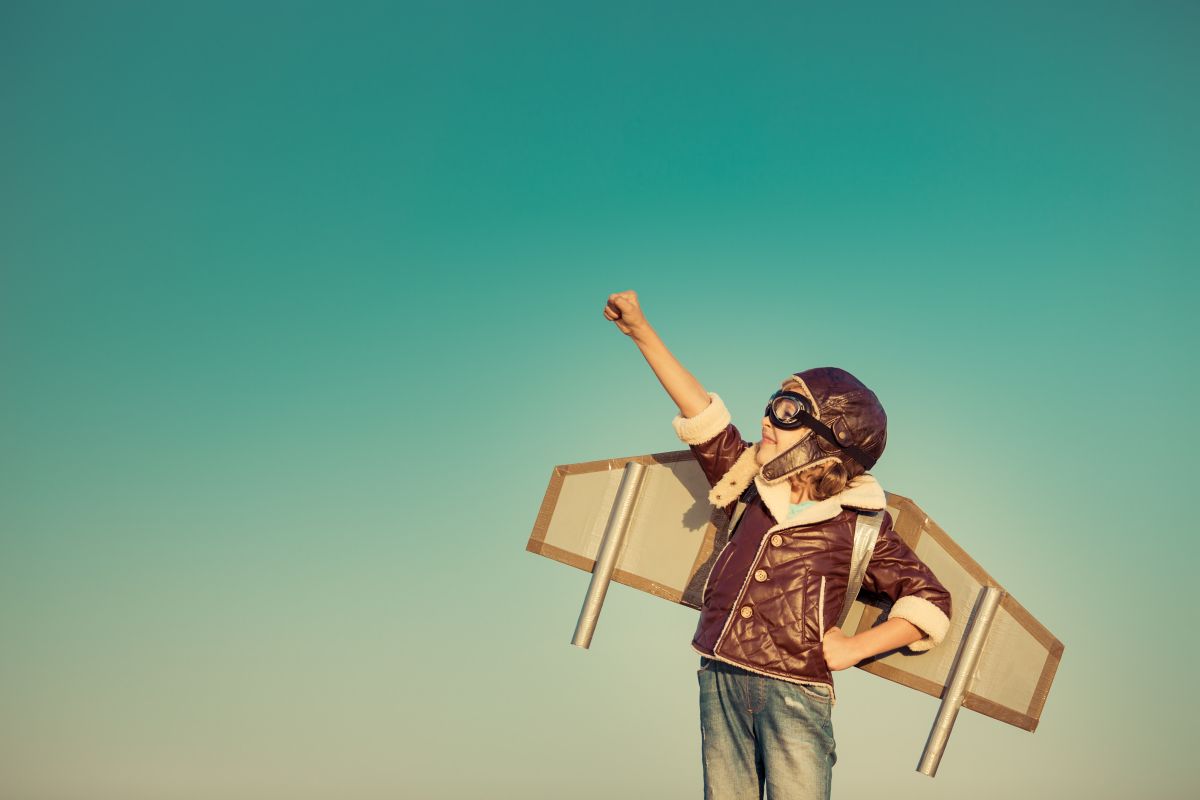 Durch Gewalterfahrungen altern Kinder schneller - Studie deckt auf Mödchen als Fliegerin verkleidet, streckt die Faust in die Luft