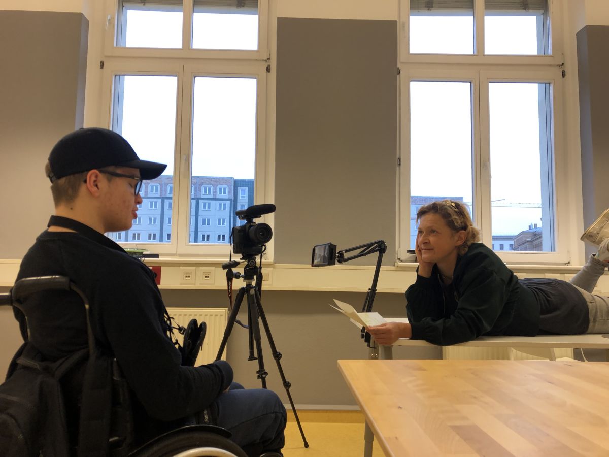 Frau interviewed Jungen im Rollstuhl.
