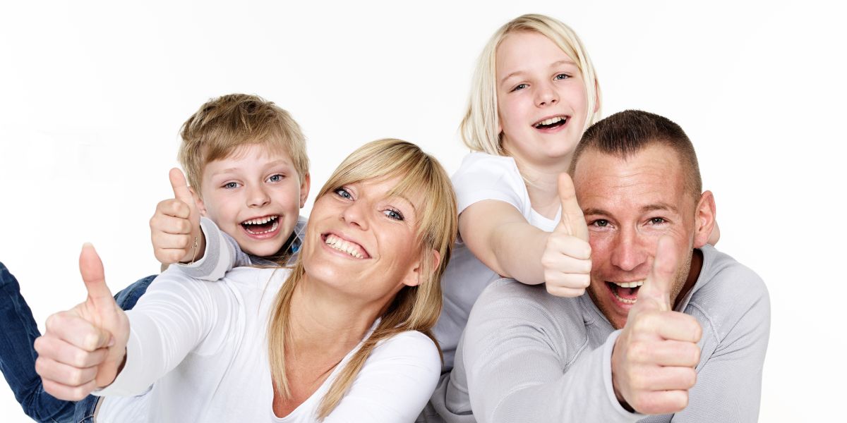Eine Familie bestehend aus Mutter, Vater, Sohn und Tochter lächeln und zeigen einen Daumen hoch.