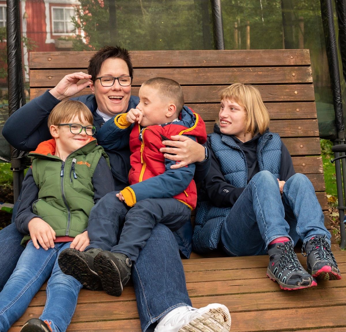 Kerstin Hed mit ihren drei Kindern sitzen auf einer Holzbank.