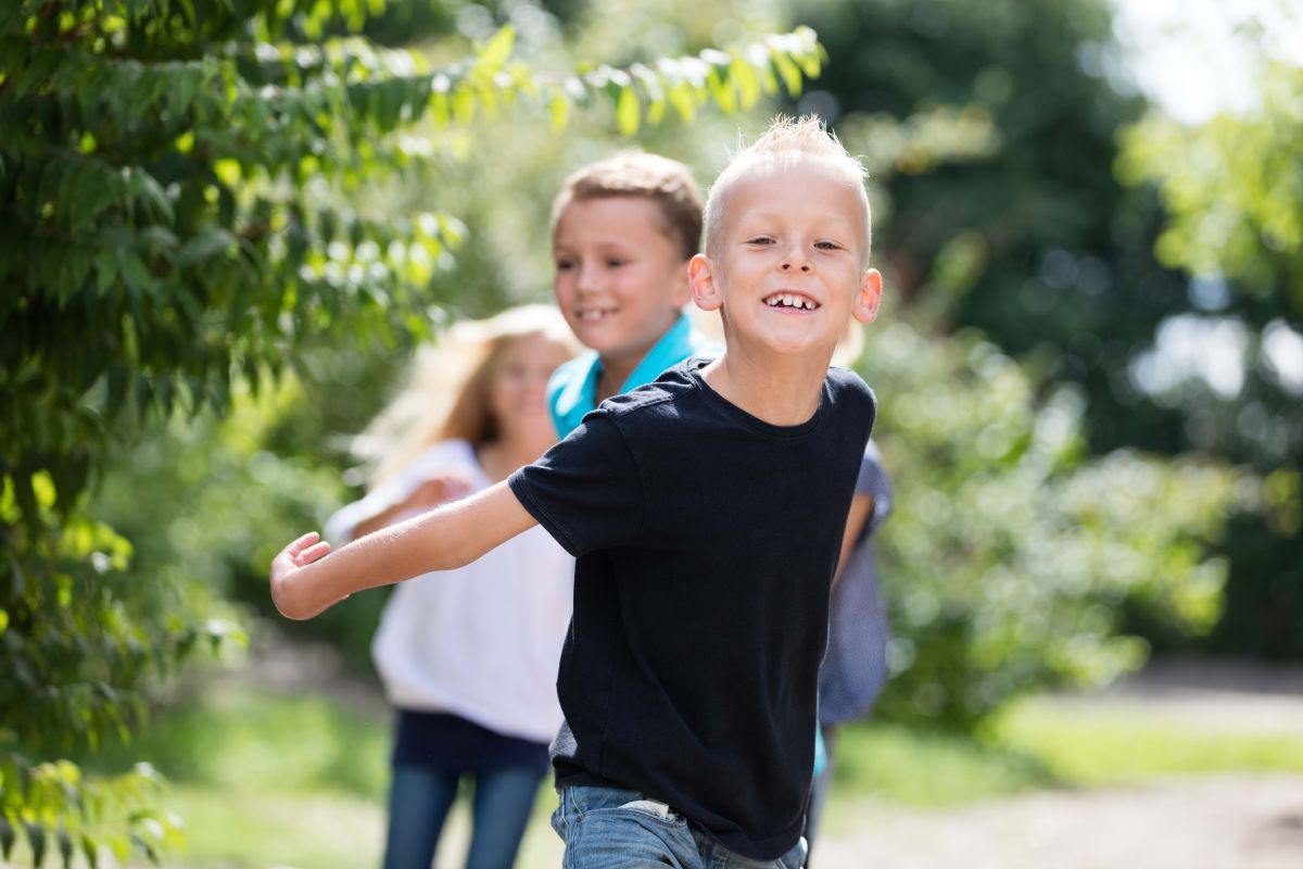 v.l.n.r.: Sohn mit Mutter, Oma und Bruder stehen gemeinsam im sommerlichen Garten.