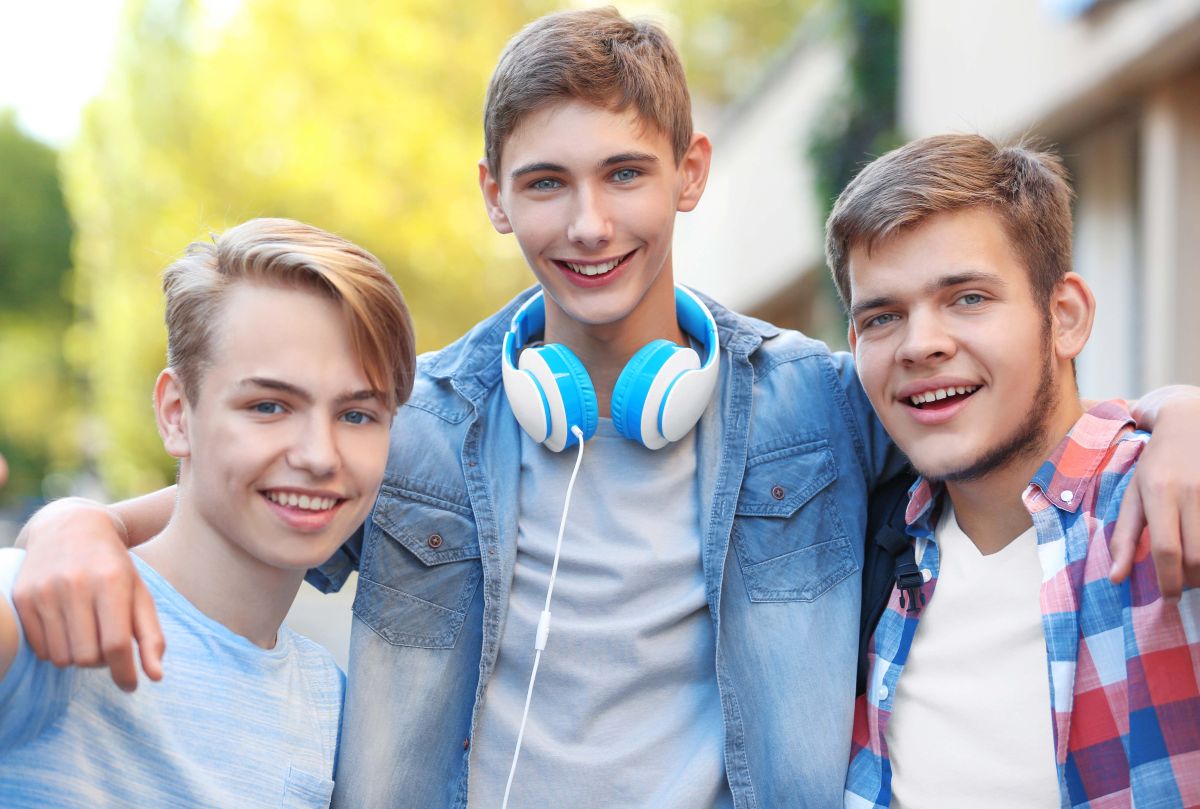 Drei Jungs in einer Umrarmung schauen lächelnd in die Kamera. Drei Jungs in einer Umrarmung schauen lächelnd in die Kamera.