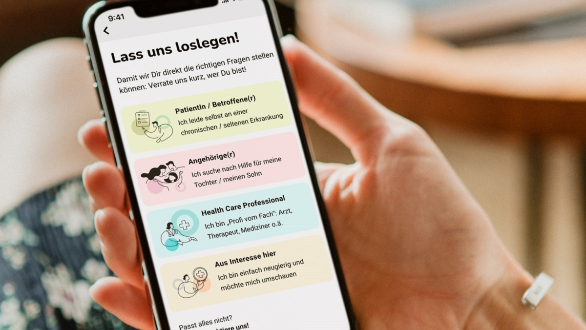 Zwei Frauenhände halten ein Handy. Darauf ist die App unrare.me zu sehen.